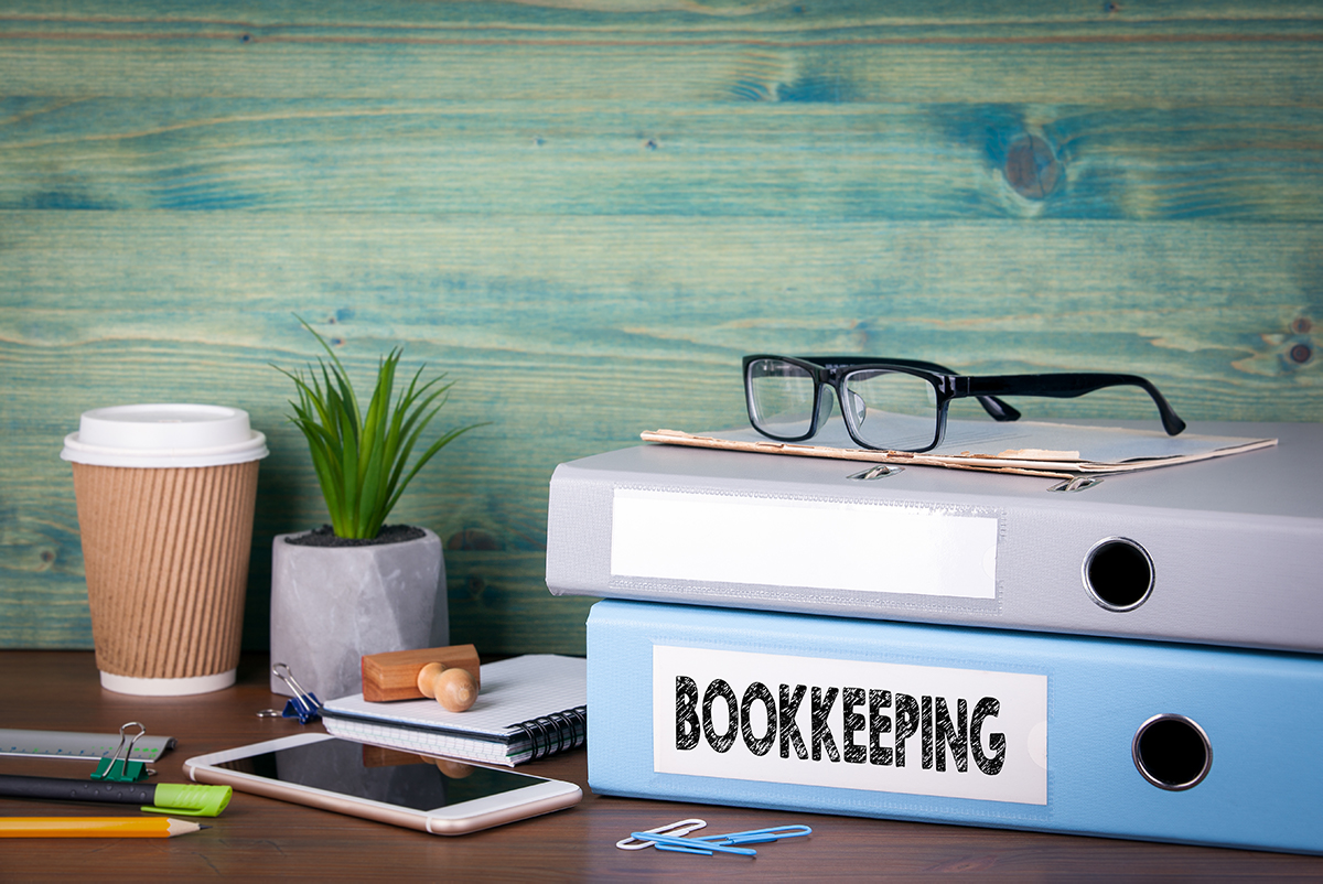 An office desk with books, a coffee cup and mobile phone.